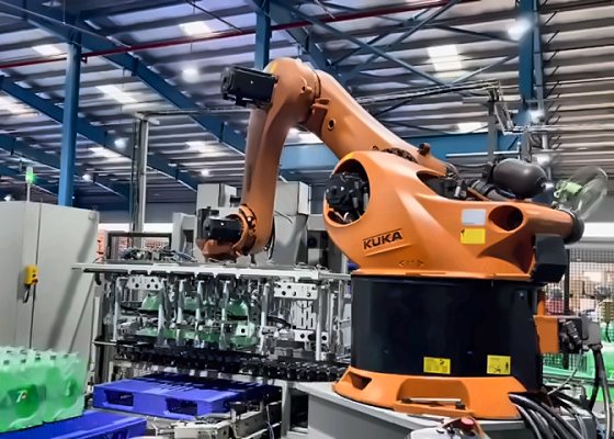 Robotic pick-and-place: an orange industrial robot with a multi-bottle gripper palletizing packs of bottles on a production line